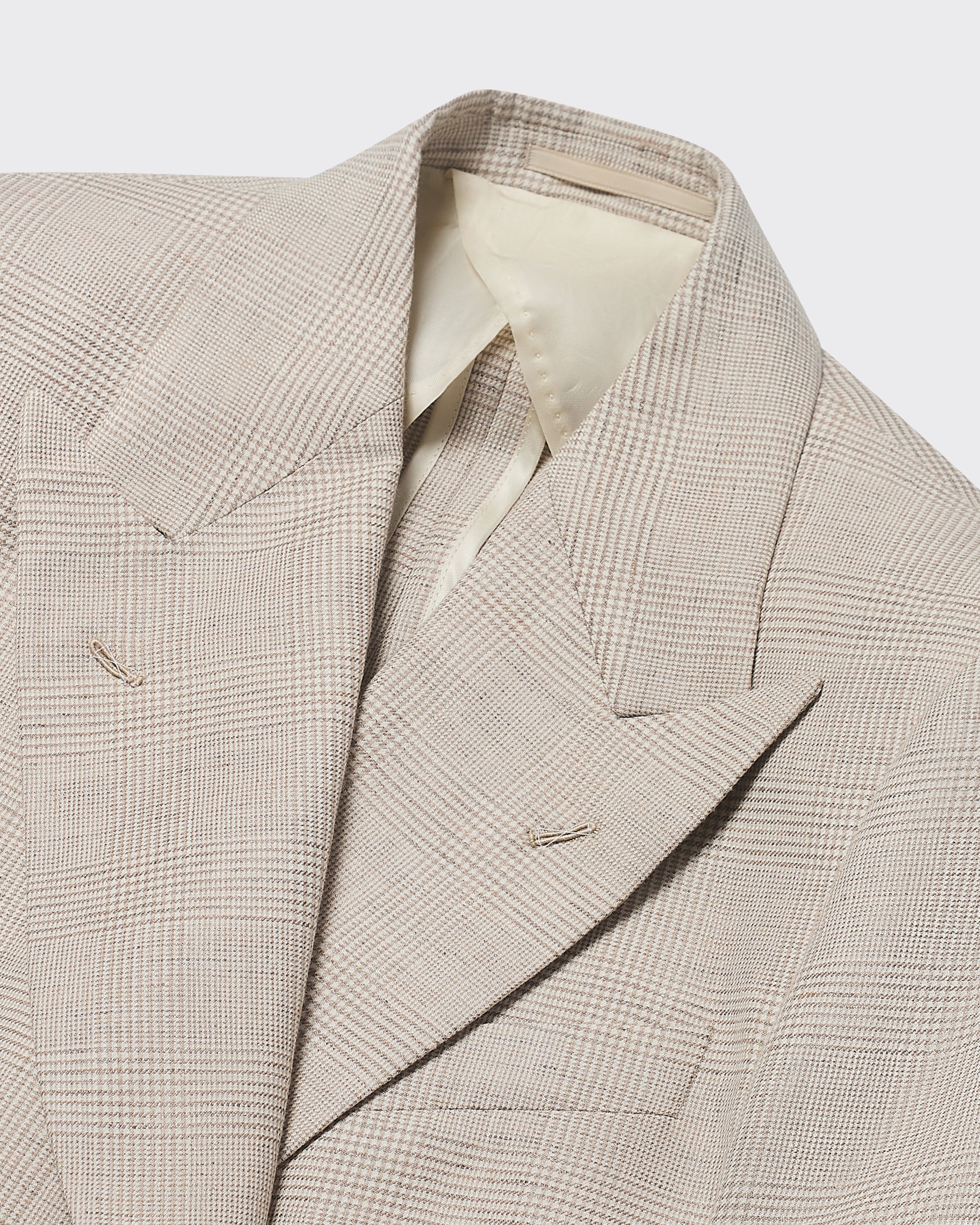 Close-up of a beige checkered blazer on a light gray background