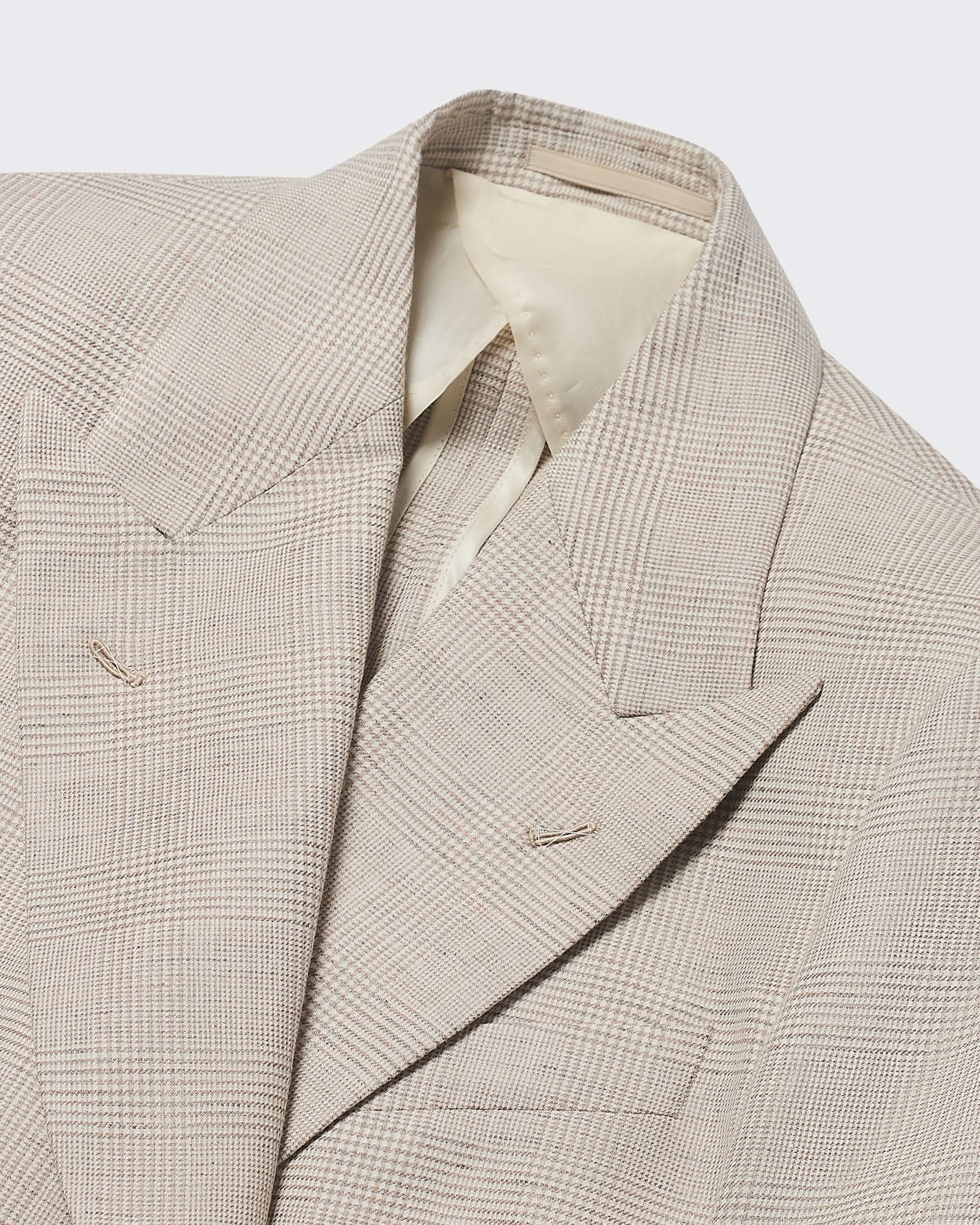 Close-up of a beige checkered blazer on a light gray background
