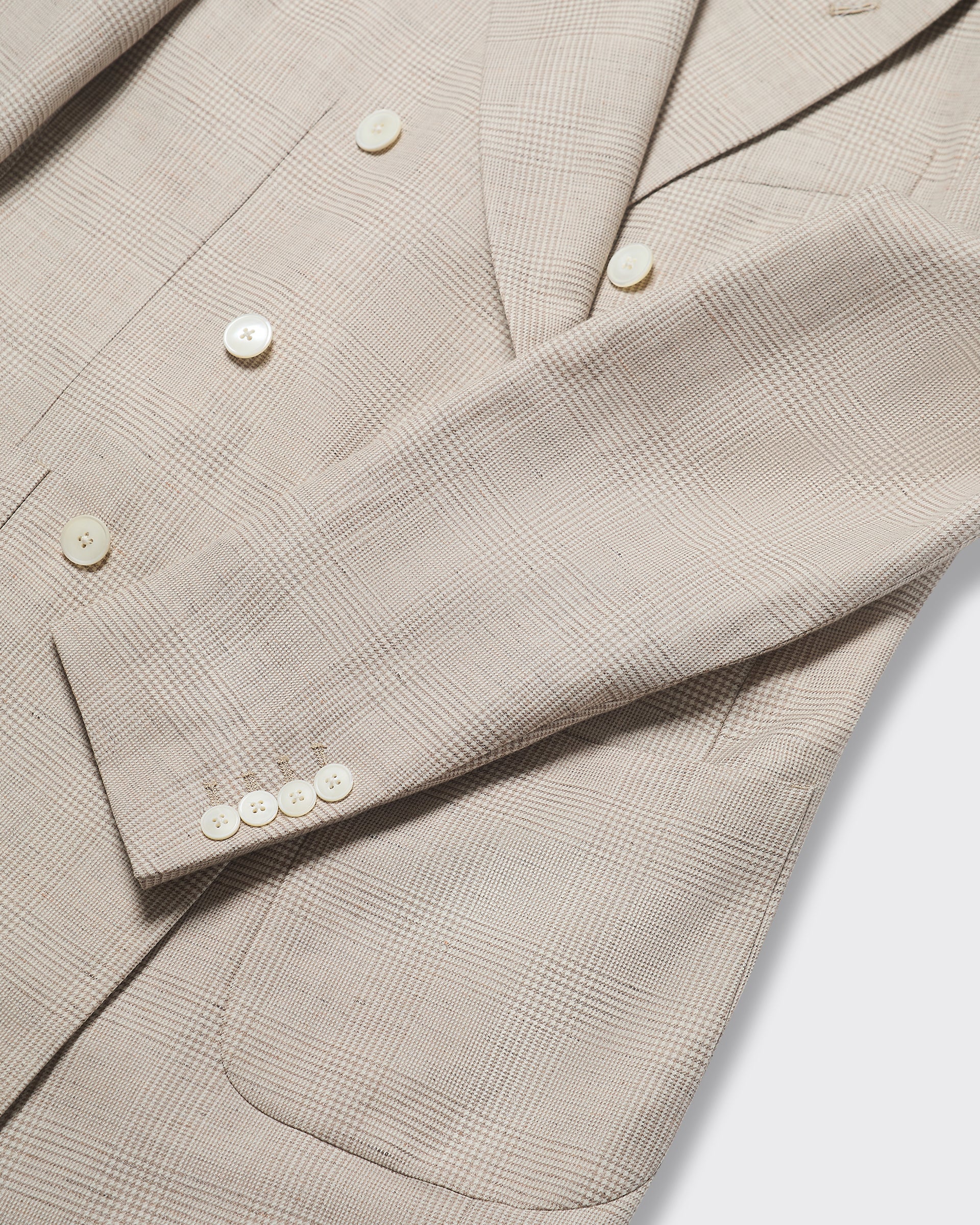 Close-up of a beige checkered blazer with buttons on a white background