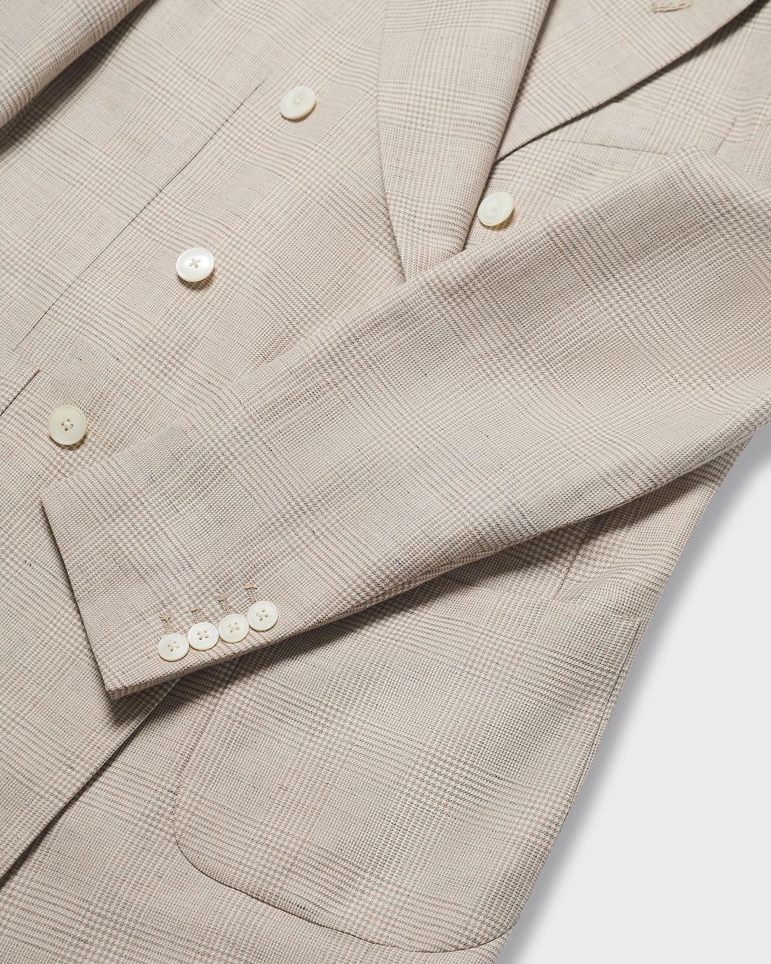 Close-up of a beige checkered blazer with buttons on a white background